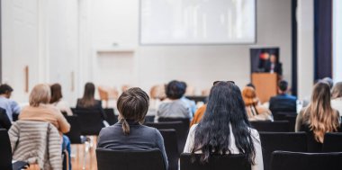 Sözcü, iş konferansında konferans salonunda konuşma yapacak. Konferans salonundaki tanınmayan insanların arka görüntüsü. İş ve girişimcilik kavramı