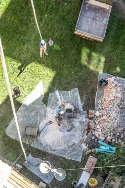 Şantiyede mikserde beton çimento çözeltisi harç hazırlama sırasında kürek ile çalışan otantik inşaatçı erkeklerin üst görünümü.
