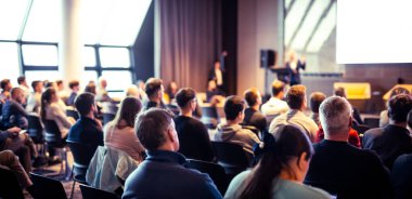 Sözcü, iş konferansında konferans salonunda konuşma yapacak. Konferans salonundaki tanınmayan insanların arka görüntüsü. İş ve girişimcilik kavramı