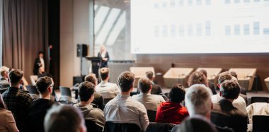 Kadın konuşmacı şirket iş konferansı hakkında bir konuşma yapıyor. Konferans salonundaki tanınmayan insanlar. İş ve Girişimcilik etkinliği
