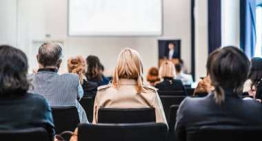 Sözcü, iş konferansında konferans salonunda konuşma yapacak. Konferans salonundaki tanınmayan insanların arka görüntüsü. İş ve girişimcilik kavramı