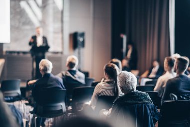 Sözcü, iş konferansında konferans salonunda konuşma yapacak. Konferans salonundaki tanınmayan insanların arka görüntüsü. İş ve girişimcilik kavramı