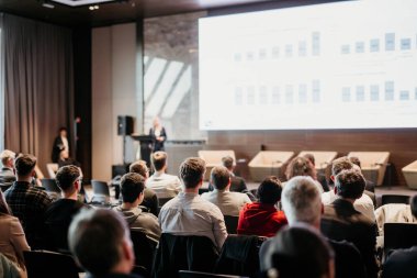 Kadın konuşmacı şirket iş konferansı hakkında bir konuşma yapıyor. Konferans salonundaki tanınmayan insanlar. İş ve Girişimcilik etkinliği