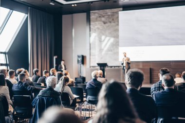 Sözcü, iş konferansında konferans salonunda konuşma yapacak. Konferans salonundaki tanınmayan insanların arka görüntüsü. İş ve girişimcilik kavramı