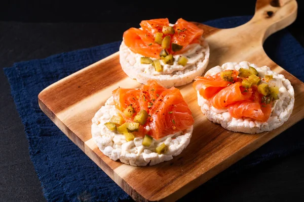 Healthy food non gluten Smoked Salmon canape Smoked salmon with rice cracker on wooden board on black slate stone