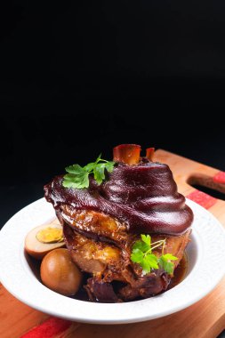 Asian food concept Chinese 5 Spice Braised Pork Knuckle on wooden board on black slate stone background with copy space