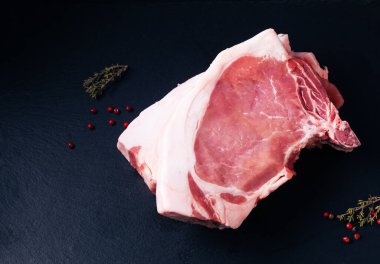 Food concept Raw organic pork chop or pork loin on black slate board with copy space
