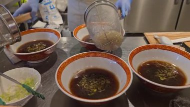 Şef yerel bir restoranda ramen pişiriyor, Japon yemekleri. Geleneksel Asya yemeklerinde erişte yapmak. Japon eriştesi olgunlaşmış ve sıcak kaynamış çorbada kaşık köftesi ile top oynuyor.