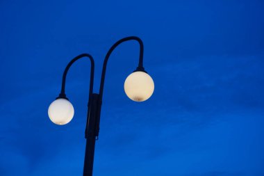 Parlayan sokak lambaları, sakin bir alacakaranlık gökyüzünü aydınlatıyor. Huzur ve sükuneti çağrıştırıyor. Şehir manzaraları, şehir manzarası tasarımları ve sakin akşam manzaraları için ideal..