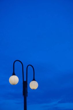 Parlayan sokak lambaları, sakin bir alacakaranlık gökyüzünü aydınlatıyor. Huzur ve sükuneti çağrıştırıyor. Şehir manzaraları, şehir manzarası tasarımları ve sakin akşam manzaraları için ideal..