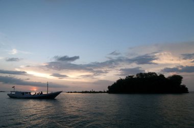 Arkadaşlarınla muhteşem bir okyanus gün batımı seyahatinin tadını çıkar. Bu sakin sahne, macerayı, rahatlamayı ve tropikal bir yerin güzelliğini çağrıştırıyor..