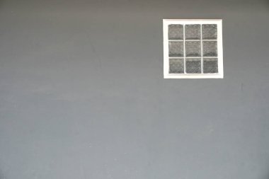 Temiz, modern gri bir duvar, ince bir ışık ve dokulu bir detay sunan küçük, beyaz çerçeveli bir cam blok pencereye sahiptir. Minimalist altyapı ve mimari kavramlar için mükemmel..
