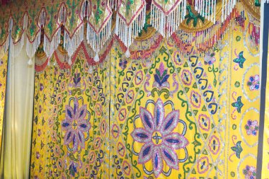 Bu zengin, sarı kumaşın ihtişamlı güzelliğini hissedin. Karmaşık çiçek desenleri ve parıldayan boncuklu süslemeler kutlama için mükemmel lüks, şenlikli bir atmosfer yaratır..