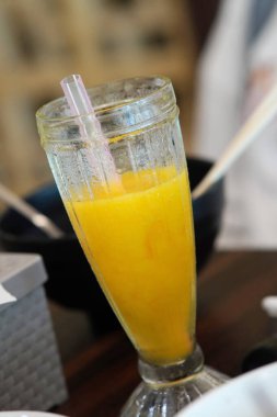 Enjoy a refreshing mango smoothie in a glass with a straw, perfect for a vibrant, healthy summer treat. A delicious tropical escape!