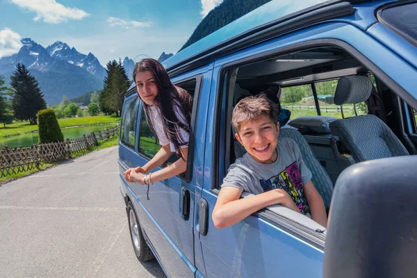 Summer holidays, road trip, vacation, travel and people concept - smiling child in minivan car in the mountains Dolomites. High quality photo
