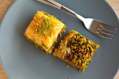 Şam fıstıklı Baklava, Türk mutfağının en güzel tatlılarından biri, Türk tatlı baklavası, gri tabakta, meşe ağacı kesme tahtasında.