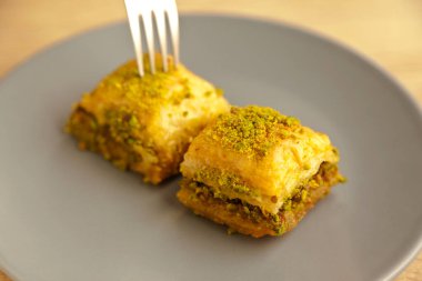 Şam fıstıklı Baklava, Türk mutfağının en güzel tatlılarından biri, Türk tatlı baklavası, gri tabakta, meşe ağacı kesme tahtasında.