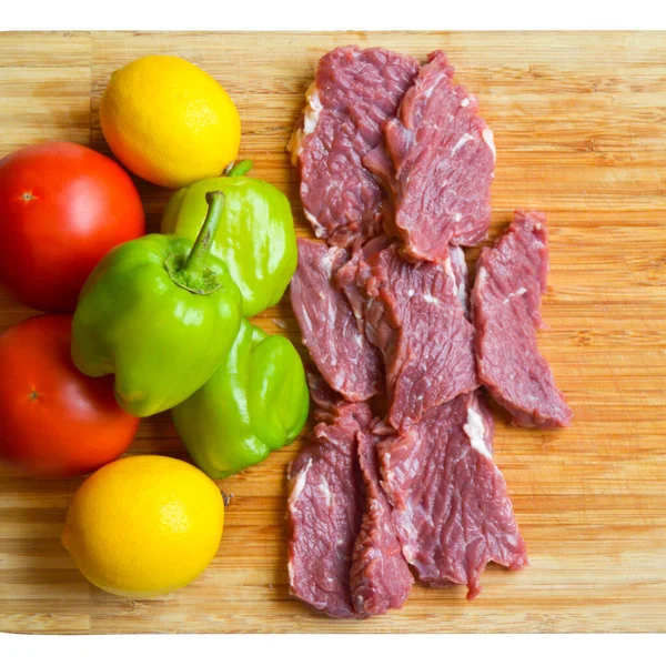 stock image Clean red raw cow meat beef, and very fresh vegetables on bamboo cutting board, white isolated