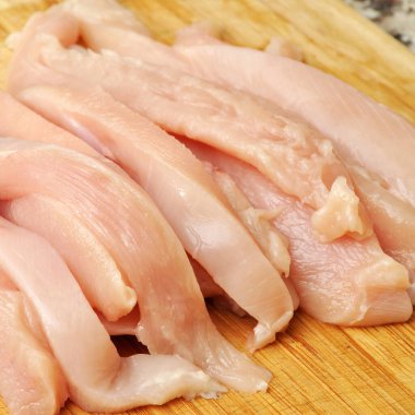 Taze çiğ tavuk eti göğüs parçaları, pişirmeye hazır, kesme tahtasında.