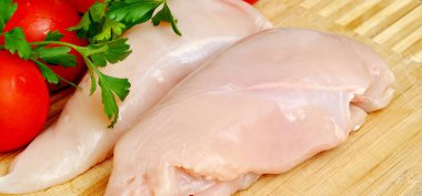 Taze çiğ tavuk eti göğüs parçaları, pişirmeye hazır, domates ve maydanozlu.