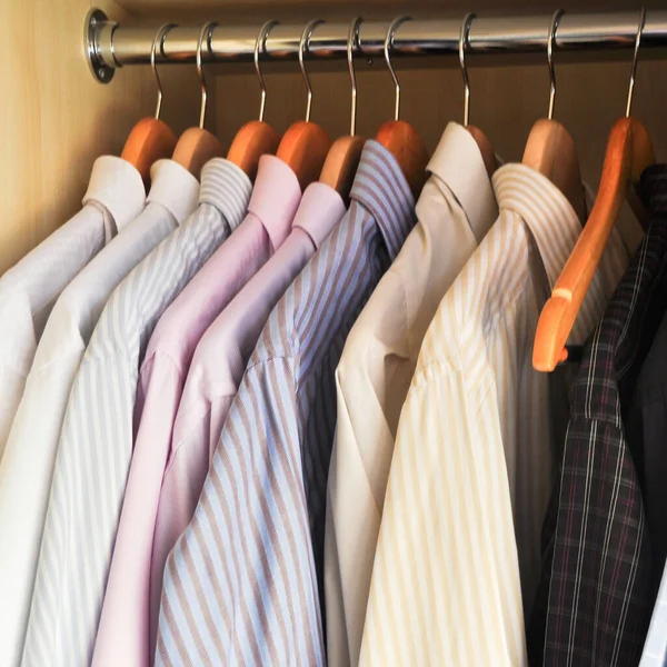 stock image Clean and modern men's shirts hanging in a wooden wardrobe