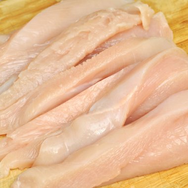 Taze çiğ tavuk eti göğüs parçaları, pişirmeye hazır, kesme tahtasında.