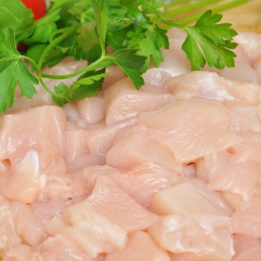 Taze çiğ tavuk eti göğüs parçaları, pişirmeye hazır, domates ve maydanozlu.