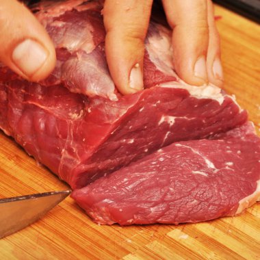 Kesme tahtasında taze kırmızı çiğ inek eti ve keskin bir bıçak var.