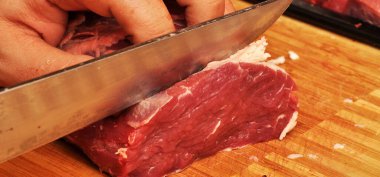 Kesme tahtasında taze kırmızı çiğ inek eti ve keskin bir bıçak var.