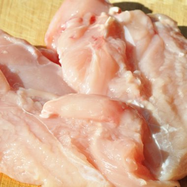 Taze çiğ tavuk eti göğüs parçaları, pişirmeye hazır, kesme tahtasında.