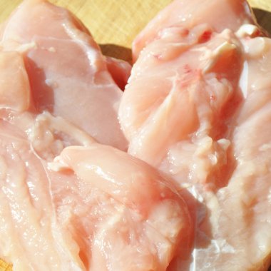 Taze çiğ tavuk eti göğüs parçaları, pişirmeye hazır, kesme tahtasında.