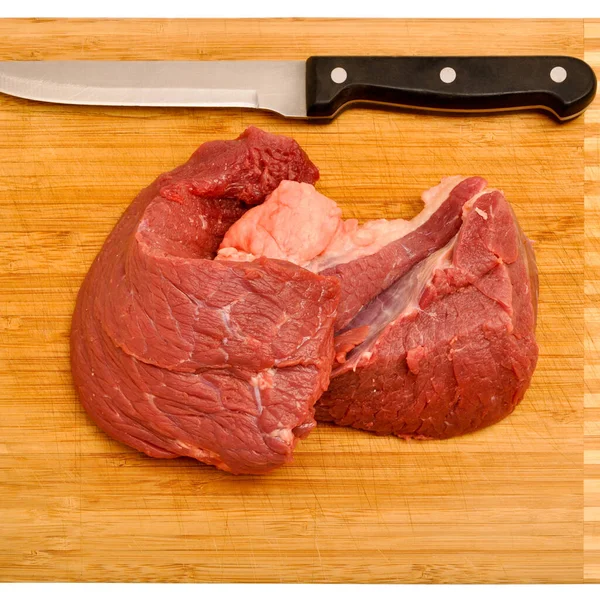 Clean very fresh red raw cow meat and a sharp knife, on cutting board and isolated white background