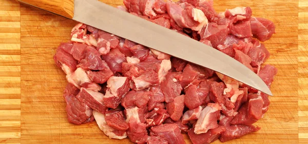 Clean very fresh red raw cow meat and a sharp knife, on cutting board