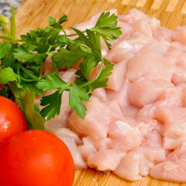 Taze çiğ tavuk eti göğüs parçaları, pişirmeye hazır, domates ve maydanozlu.