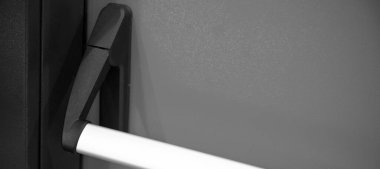 Acil çıkış kapısı. Kapalı kapı mandalı ve acil çıkış kapısının siyah beyaz kolu. Panik çıkışı için parmaklıkları itin.