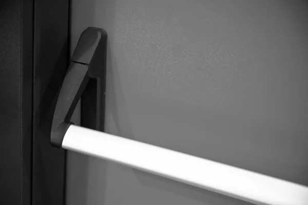 Emergency exit door. Closed up latch and black white door handle of emergency exit. Push bar and rail for panic exit