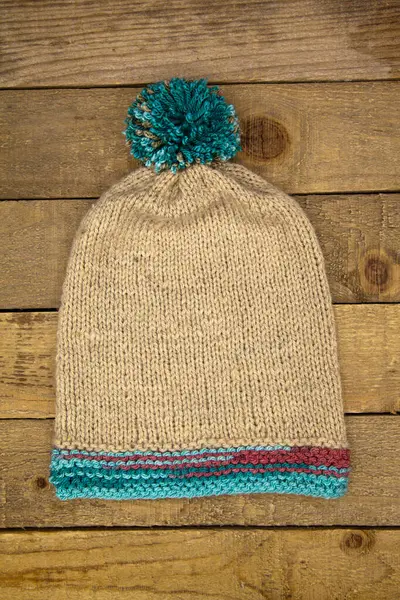 木制背景的手工毛织冬帽 — 图库照片