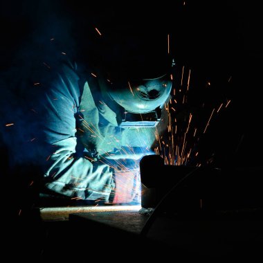 Kaynakçı, metal ekipman üretiminde kıvılcım çıkarmak için meşale kullanır. Profesyonel kaynak ustası.