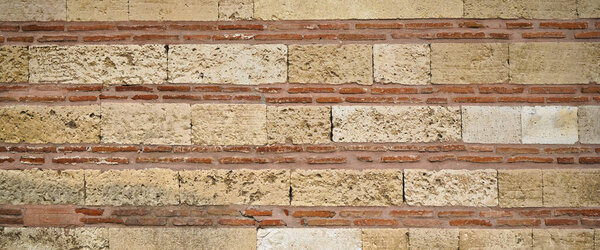 Sturdy yellow and beige cut stone brick wall, good for backgrounds, seamless lined up