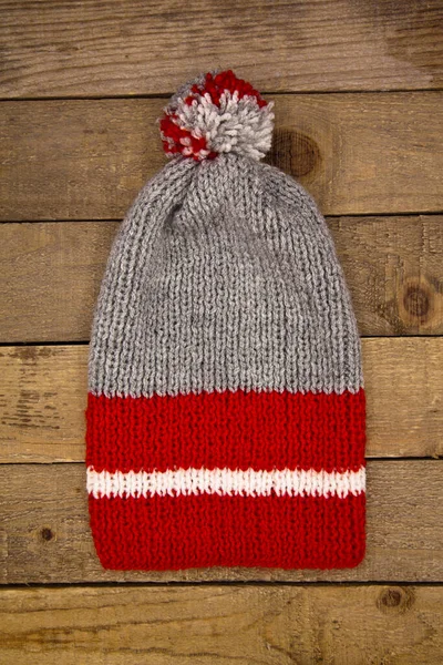 Handmade wool knitted winter red grey hat and scarf isolated on old wood background