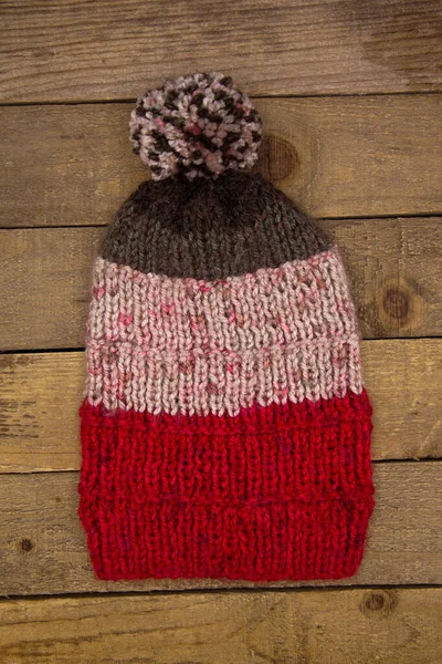 Handmade wool knitted winter red white hat and scarf isolated on old wood background