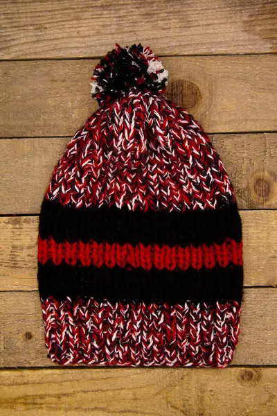 Handmade wool knitted winter red black hat and scarf isolated on old wood background