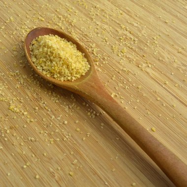 Kuru çatlamış buğday daliya tahılları tahta kaşıkta, bambu kesme tahtasında