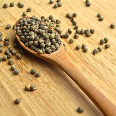 Tahta kaşıkta, bambu kesme tahtasının üzerinde kurutulmuş bamya tohumları.