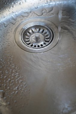 Stainless steel sink and water drain in a modern kitchen, water flow in the kitchen sink, water goes from the drain clipart