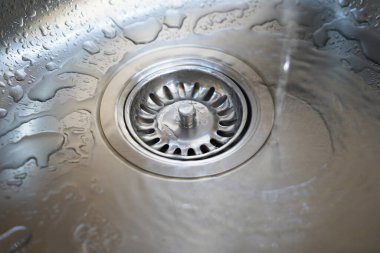 Paslanmaz çelik lavabo ve su modern bir mutfakta akıyor. Mutfak lavabosunda su akıyor. Su kanalizasyondan akıyor.