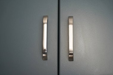 Gri kaplı mutfak dolabı ve krom paslanmaz kapı kolu, lüks mutfak ekipmanları.