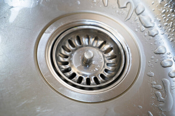 Stainless steel sink and water drain in a modern kitchen, water flow in the kitchen sink, water goes from the drain