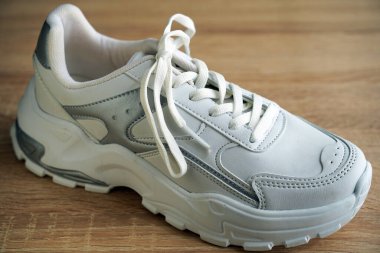 Yeni şık ve kullanışlı beyaz ayakkabılar, ahşap zeminde.