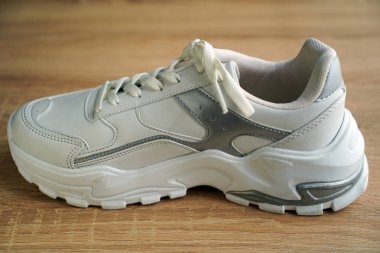 Yeni şık ve kullanışlı beyaz ayakkabılar, ahşap zeminde.